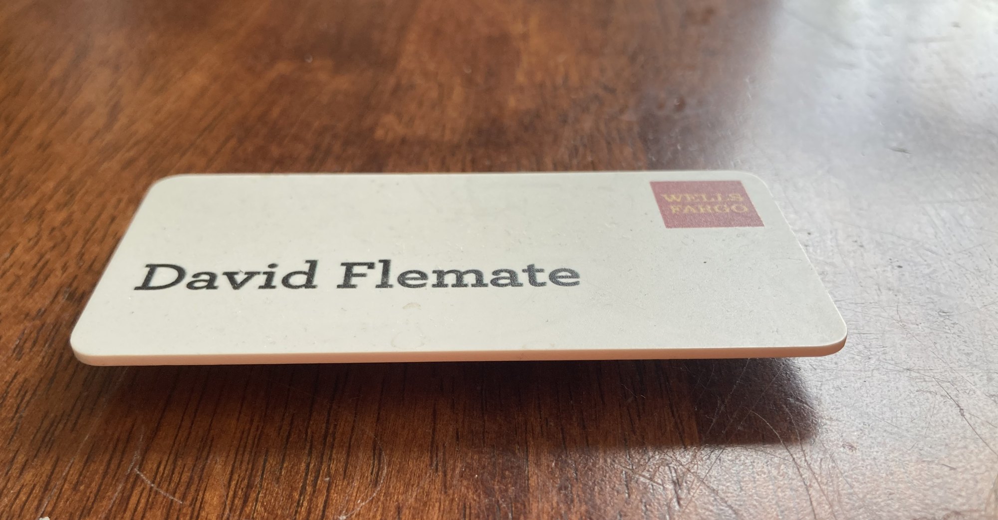 A Wells Fargo name tag reading David Flemate, resting on a wooden table